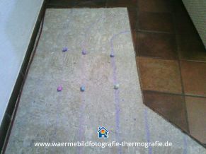 Mit Kreide werden die Positionen der Leitungen der Fußbodenheizung auf den Fußboden übertragen. Die Wärmebildkamera Bochum macht es möglich